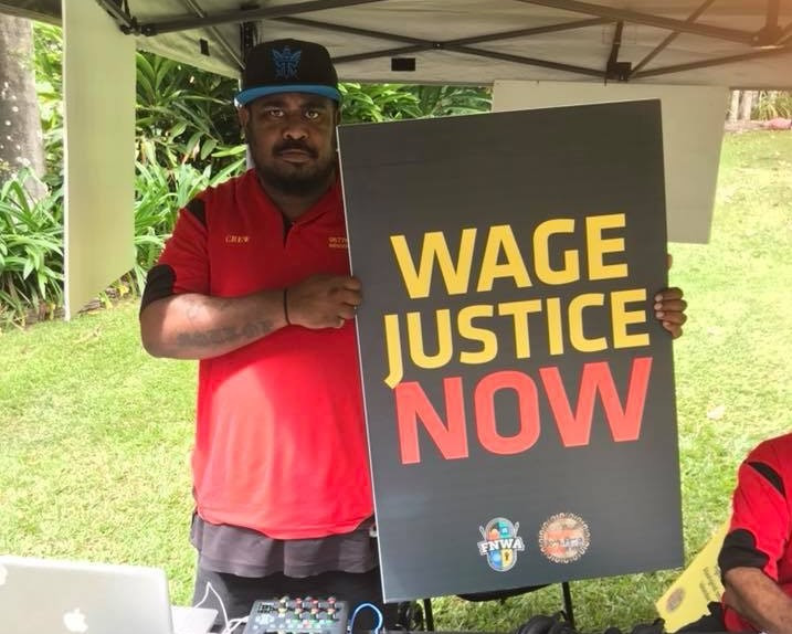 A worker holds a sign reading: 'Wage justice now' 