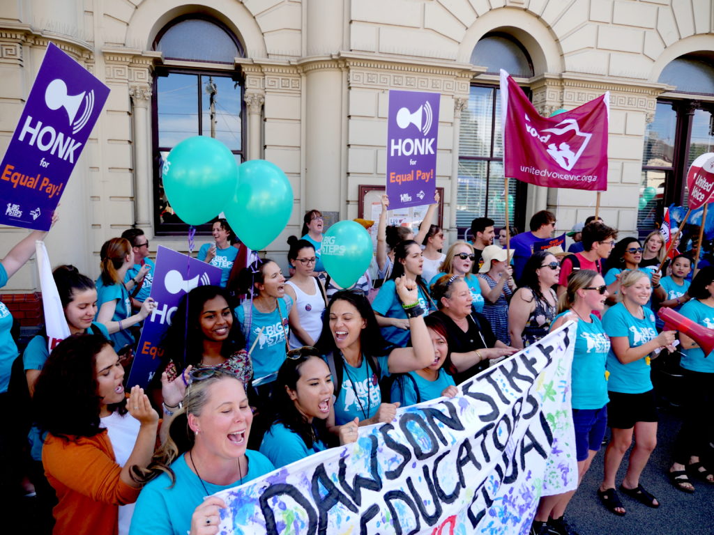 Early educators shout while holding balloons and banners