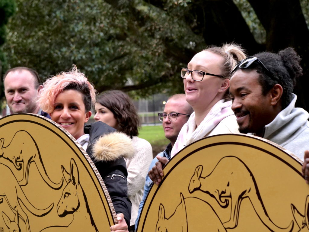 Workers stand with massive $1 coin cardboard cutouts