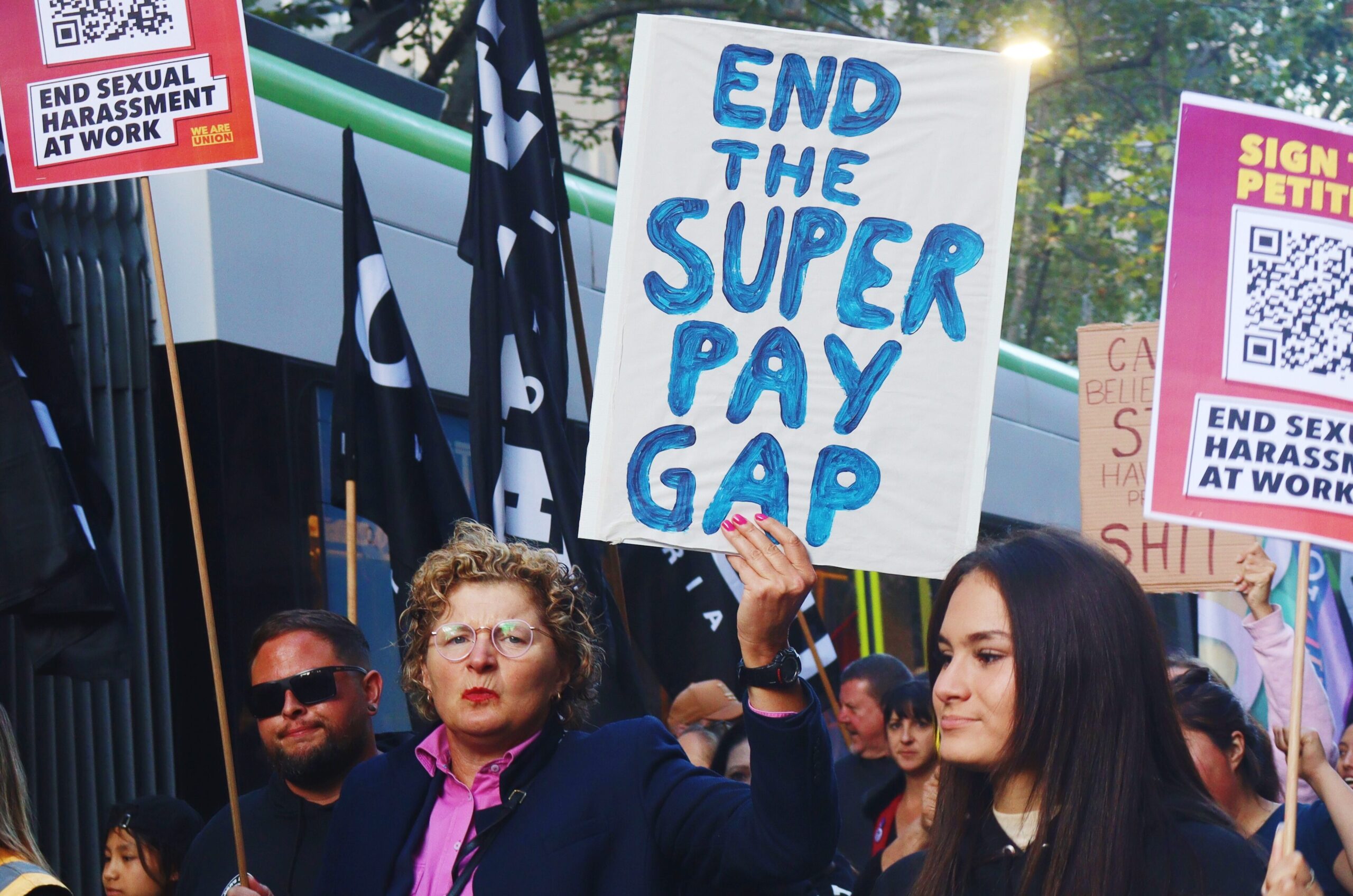A union member holds up a sign that says: 'End the super pay gap'