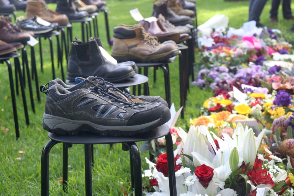 A row of pairs of shoes next to a row of floral wreaths.